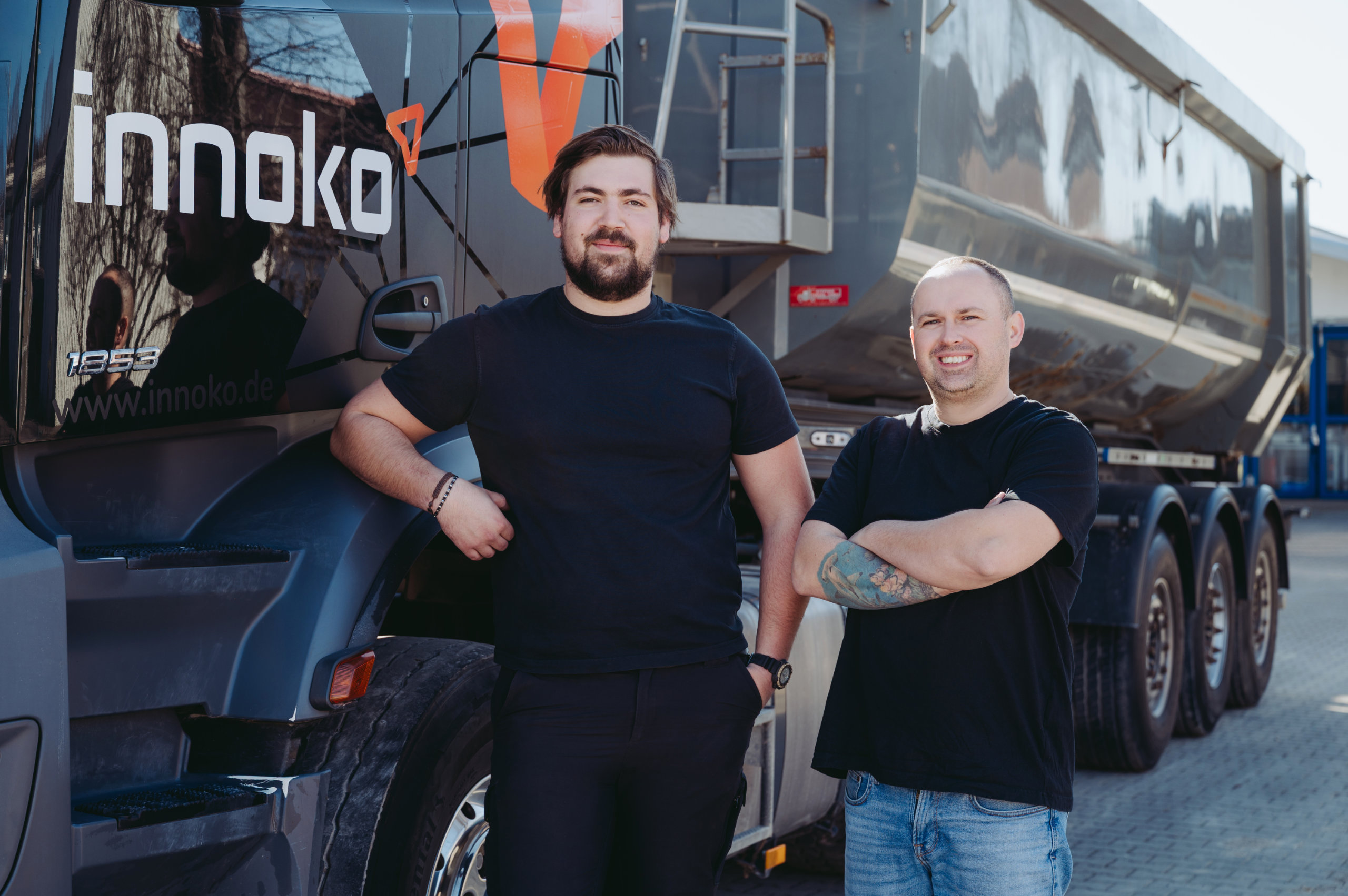 Zwei LKW-Fahrer von Innoko stehen lächelnd vor LKW