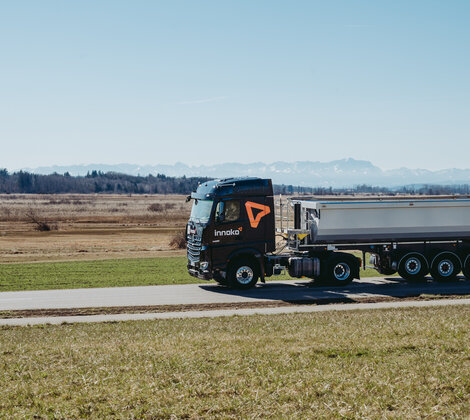 ein schwarzer Innoko Lkw fähr auf einer Landstraße durchs Grüne